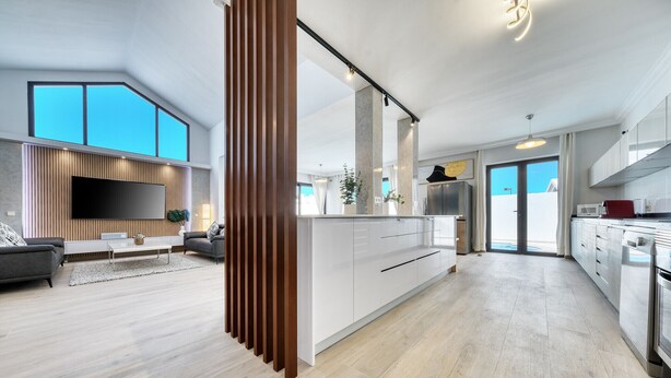 A modern kitchen with white cabinets, a large island, and a built-in oven.