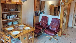 A wooden dining area with a table set for four, surrounded by shelves with glassware and plates. - Cosy apartment for 4 people with WIFI, TV and balcony (Saint-gervais-les-bains)