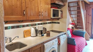 A compact kitchen with wooden cabinets, a microwave, a Bosch coffee maker, a washing machine, and a sink. - Cosy apartment for 4 people with WIFI, TV and balcony (Saint-gervais-les-bains)