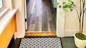 A hallway leading to a kitchen with a wooden floor, white cabinets, and a potted plant. - Crosby Street Suite - Freshly Renovated 3 Bedroom near Downtown Augusta (Augusta)