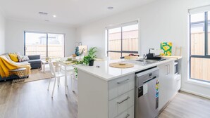 Een moderne keuken met een centraal eiland, witte kasten en een vaatwasser.
