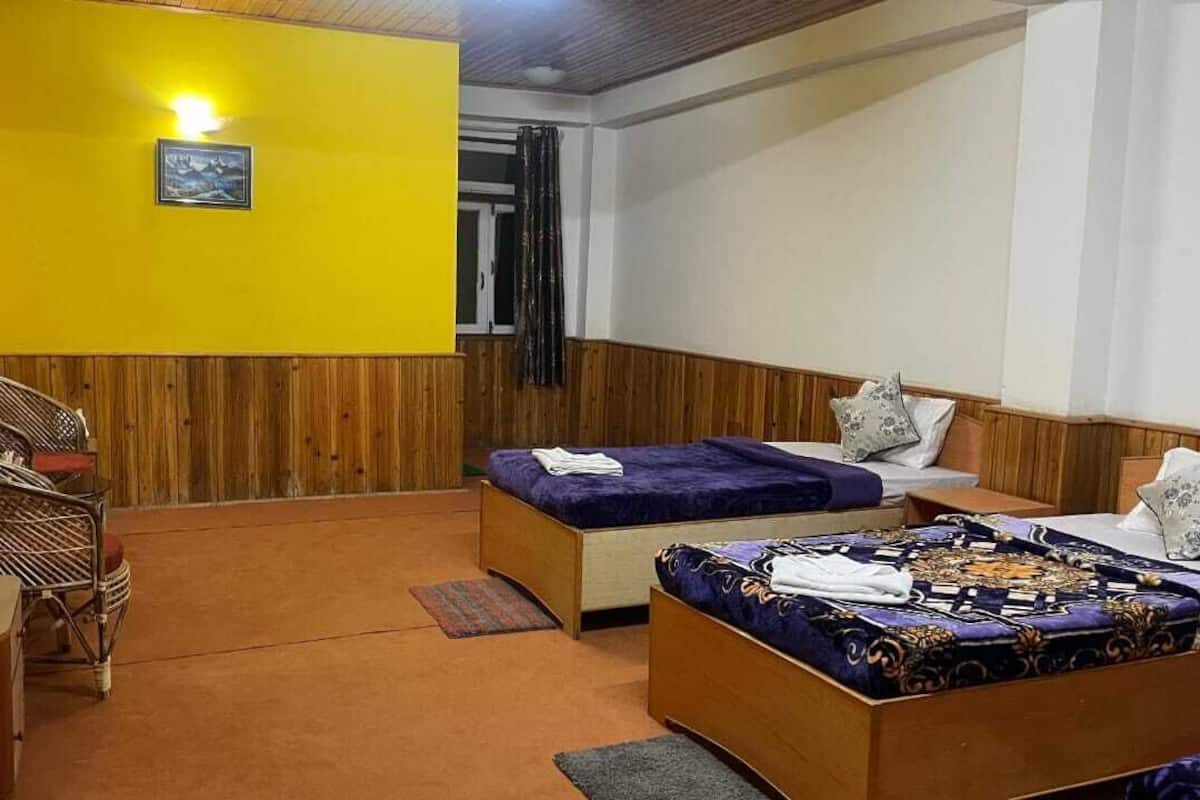 A room with a bed, a chair, a small table, and a wall-mounted shelf.