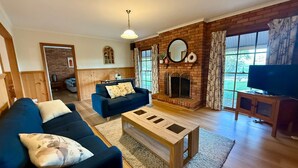 A living room with a sofa, coffee table, fireplace, television, and a brick wall.
