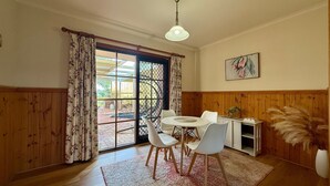 A dining area with a table and chairs, a ceiling fan, and a view through a glass door to an outdoor patio.