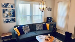 A living room with a sofa, coffee table, and artwork on the wall. - Cozy home with AC and WiFi in beautiful Flowery Branch (Flowery Branch)