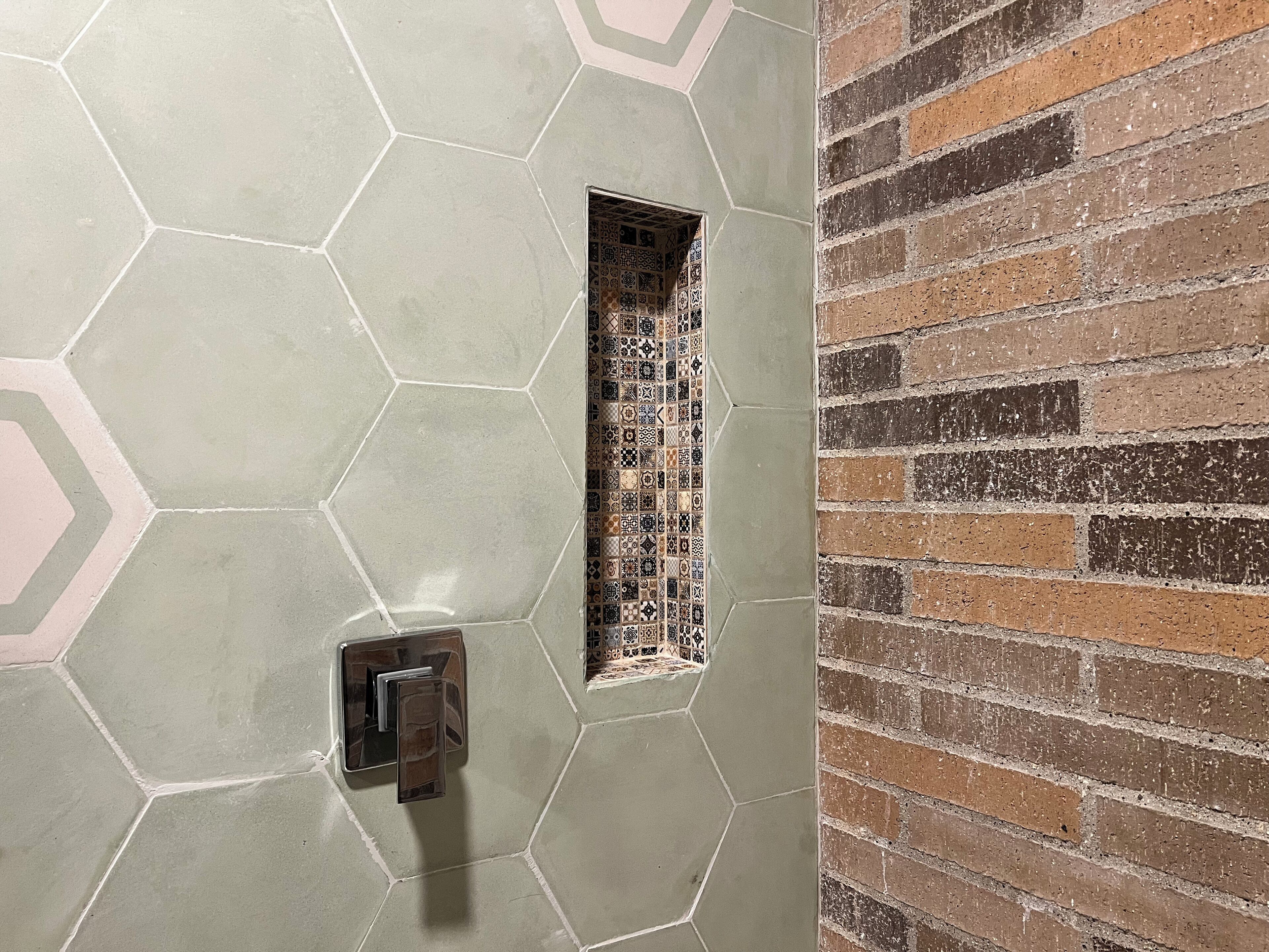 A wall with hexagonal tiles and a small window with patterned tiles.