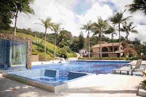 A swimming pool with tiled edges, surrounded by lounge chairs and palm trees. - Autenthico Sajonia Hotel Aeropuerto (Rionegro)