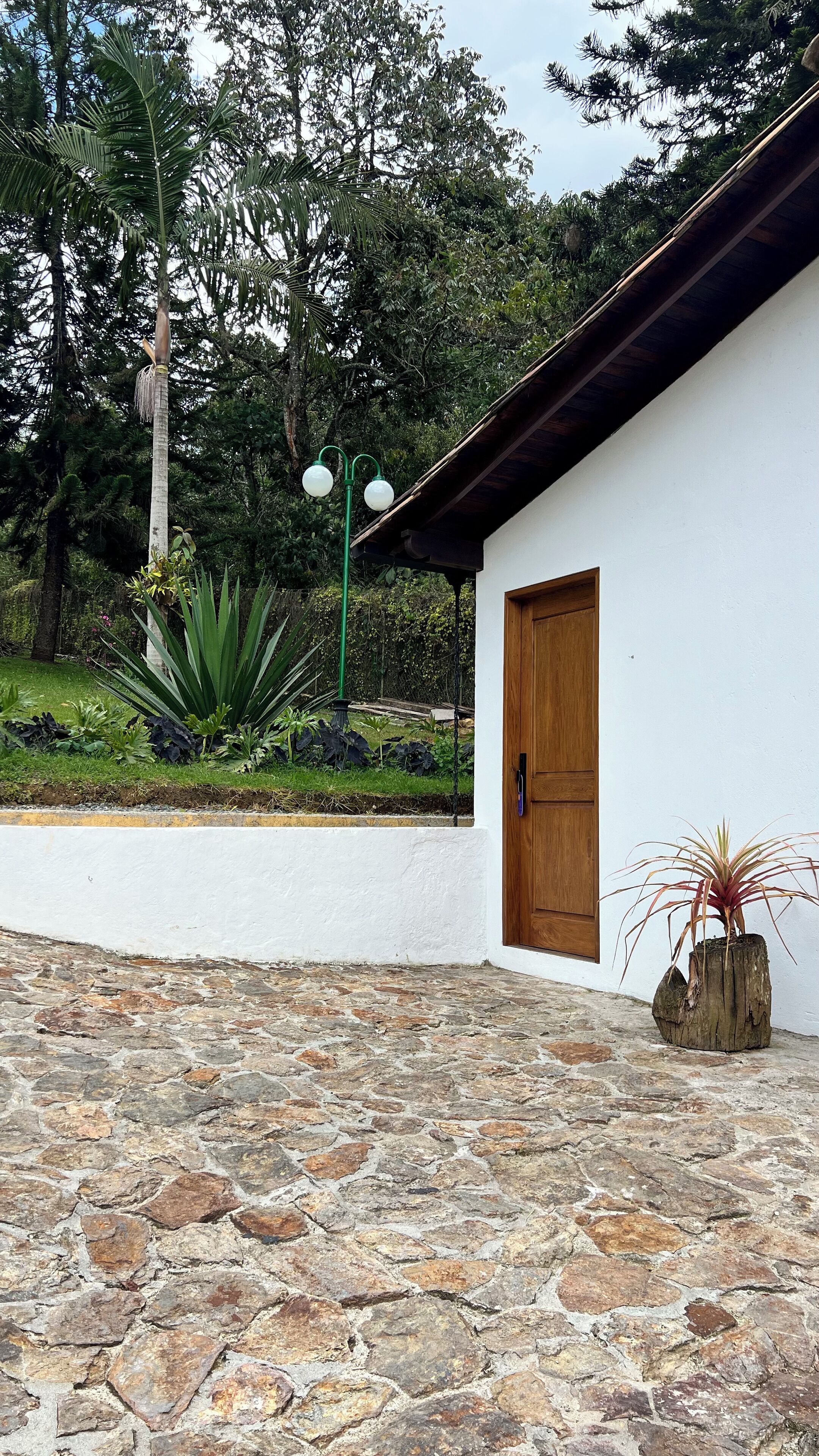 A building with a white exterior, a wooden door, and a stone-paved entrance area.