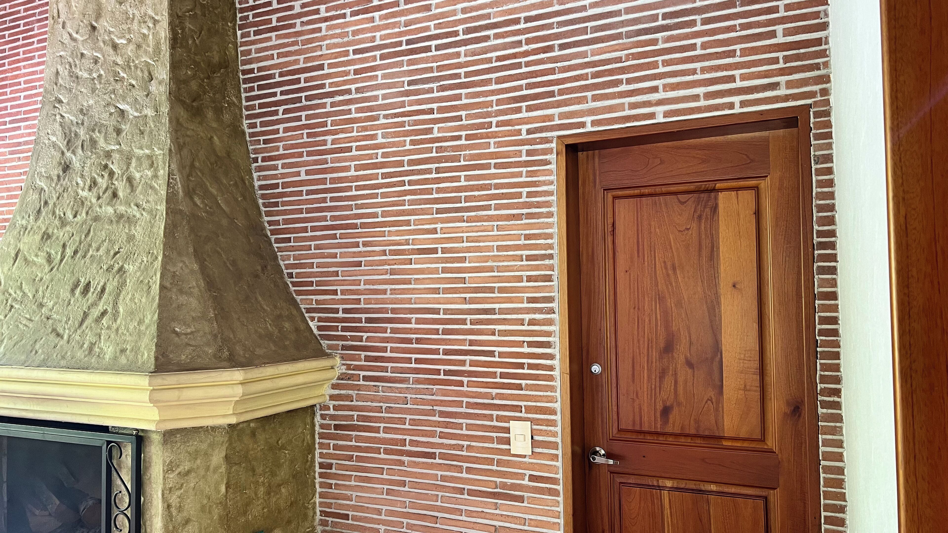 A brick wall with a wooden door and a stone chimney.