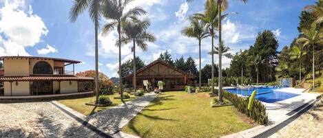 A resort with a swimming pool, a covered outdoor area, and a building with a tiled roof.