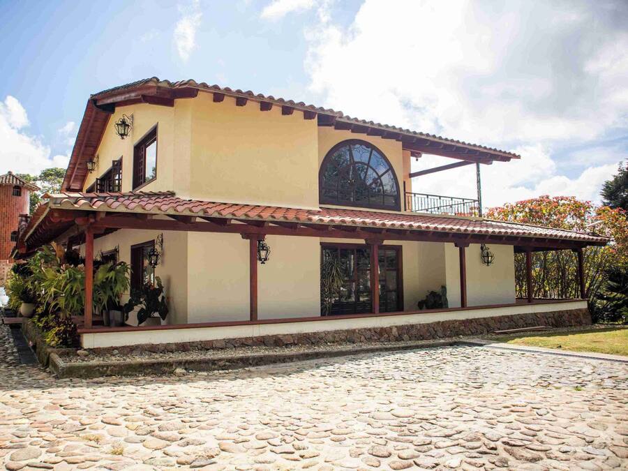 A two-story building with a tiled roof, large windows, and a stone-paved courtyard.