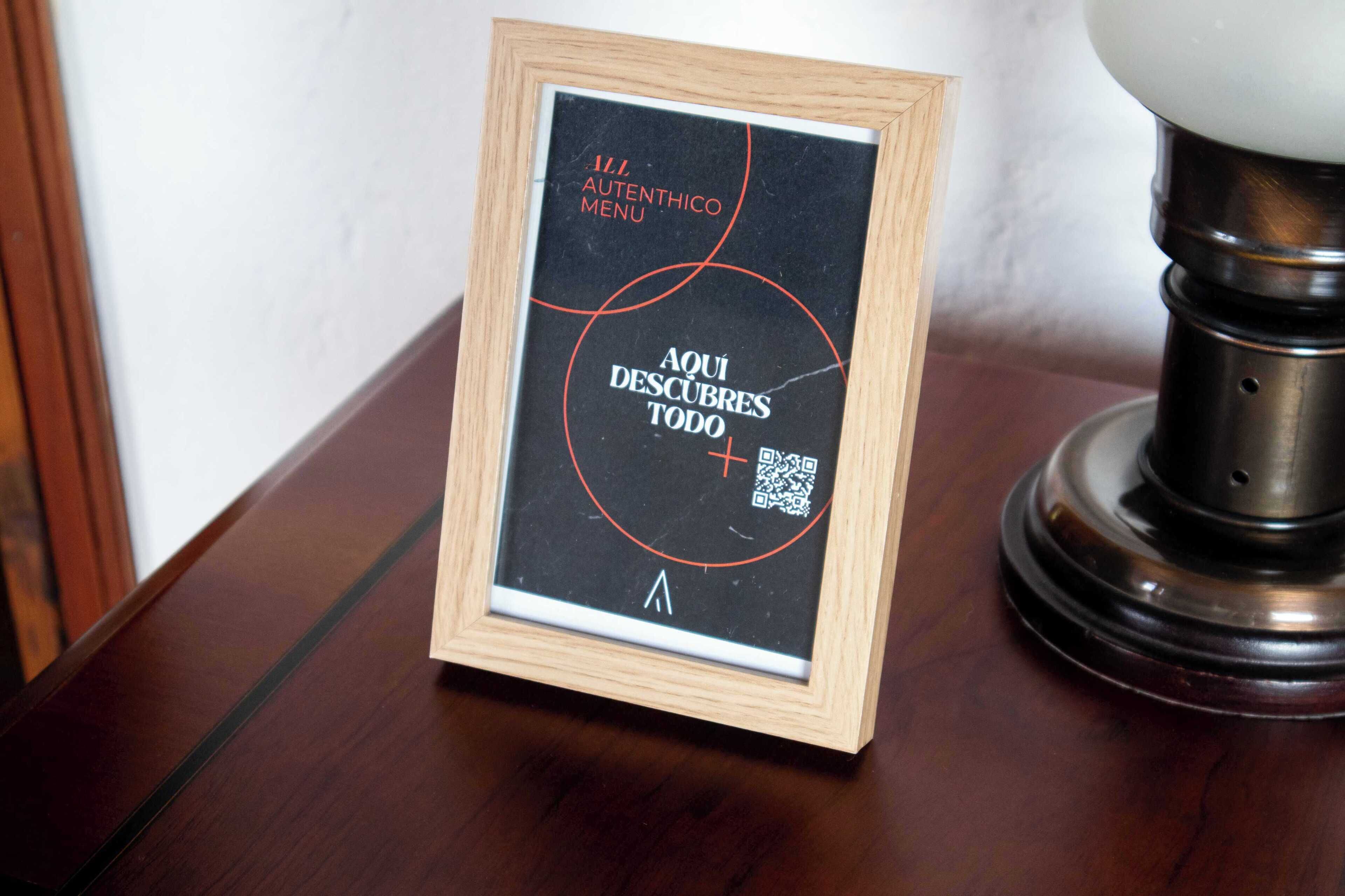 A framed sign with a QR code and text on a wooden table.