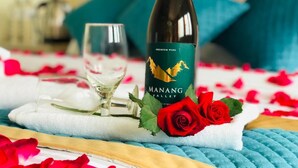 Una bottiglia di vino della Valle del Manang, un bicchiere e una rosa su un asciugamano.