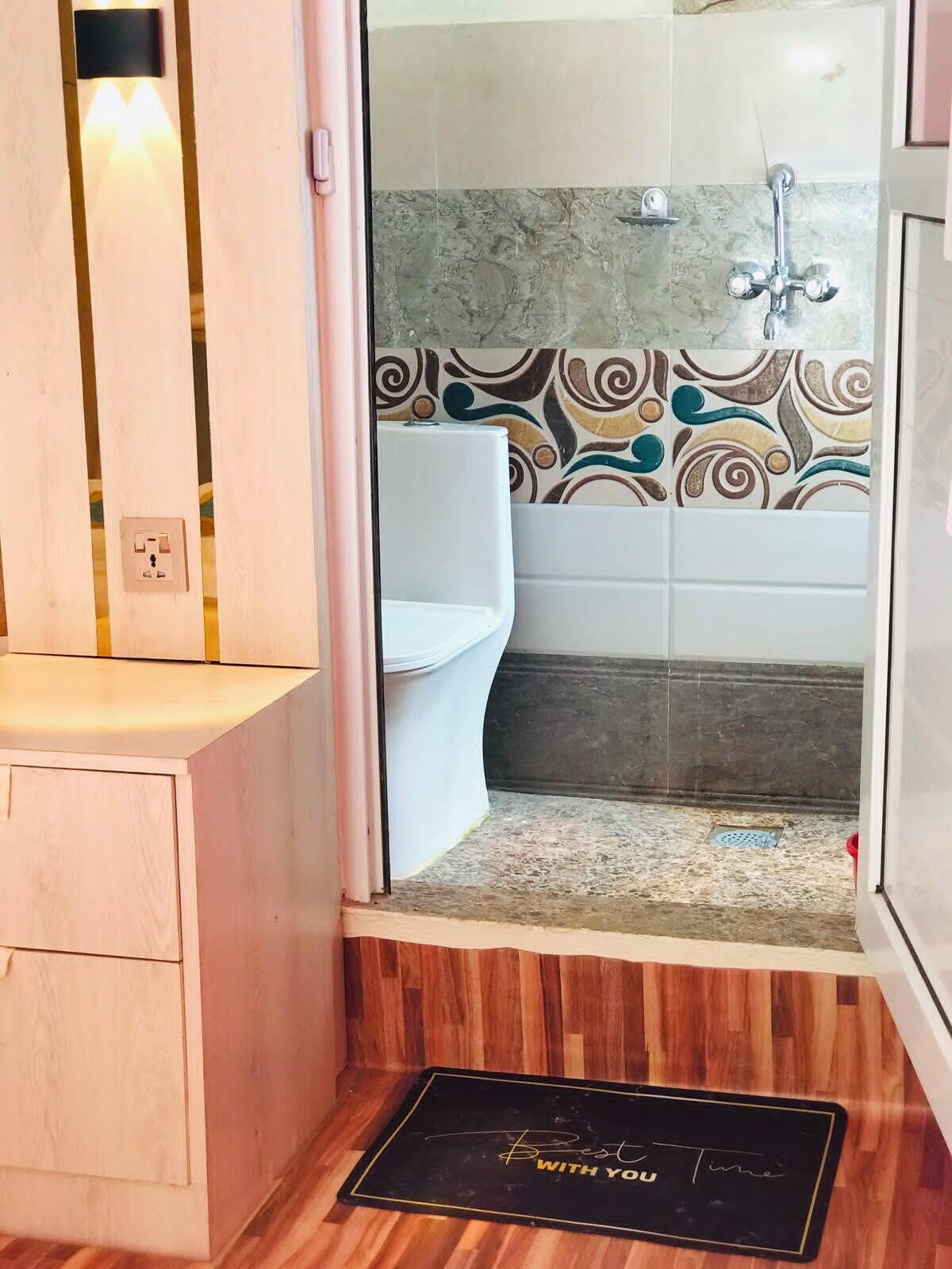 A bathroom with a shower, toilet, and a wooden vanity.