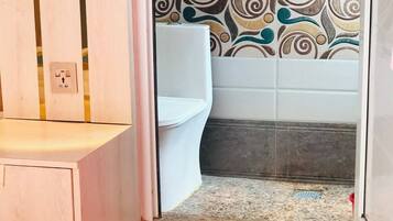 A bathroom with a shower, toilet, and a wooden vanity.