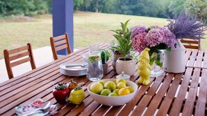 Ein Holztisch, gedeckt mit Tellern, einer Obstschale, einer Kanne, einer Blumenvase und einer dekorativen Figur.