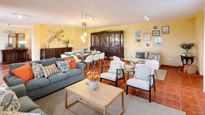 Ein Wohnzimmer mit einer Couch, Sesseln, einem Couchtisch und einem Essbereich mit Tisch und Stühlen.