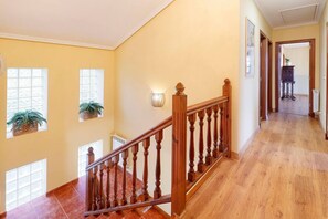 Un escalier en bois avec une rampe, un radiateur et un pot de fleurs accroché au mur.