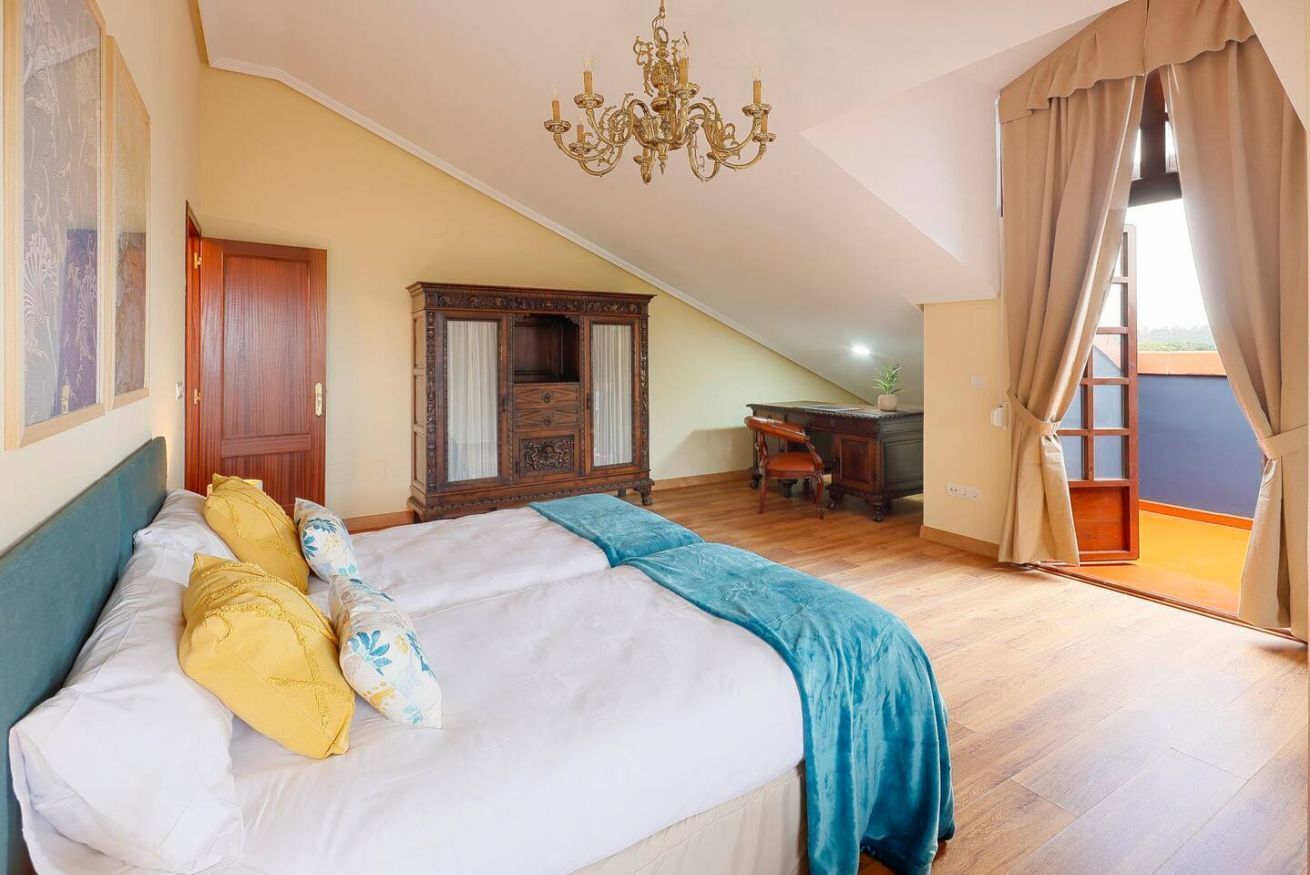 Une chambre à coucher avec un lit, un lustre, une armoire et un bureau.