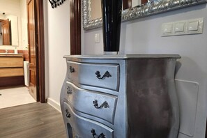 Une salle de bain avec un meuble-lavabo en bois, un grand miroir et un interrupteur fixé au mur.