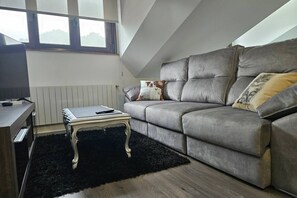Una sala de estar moderna con un sofá gris, una mesita blanca y una alfombra negra.