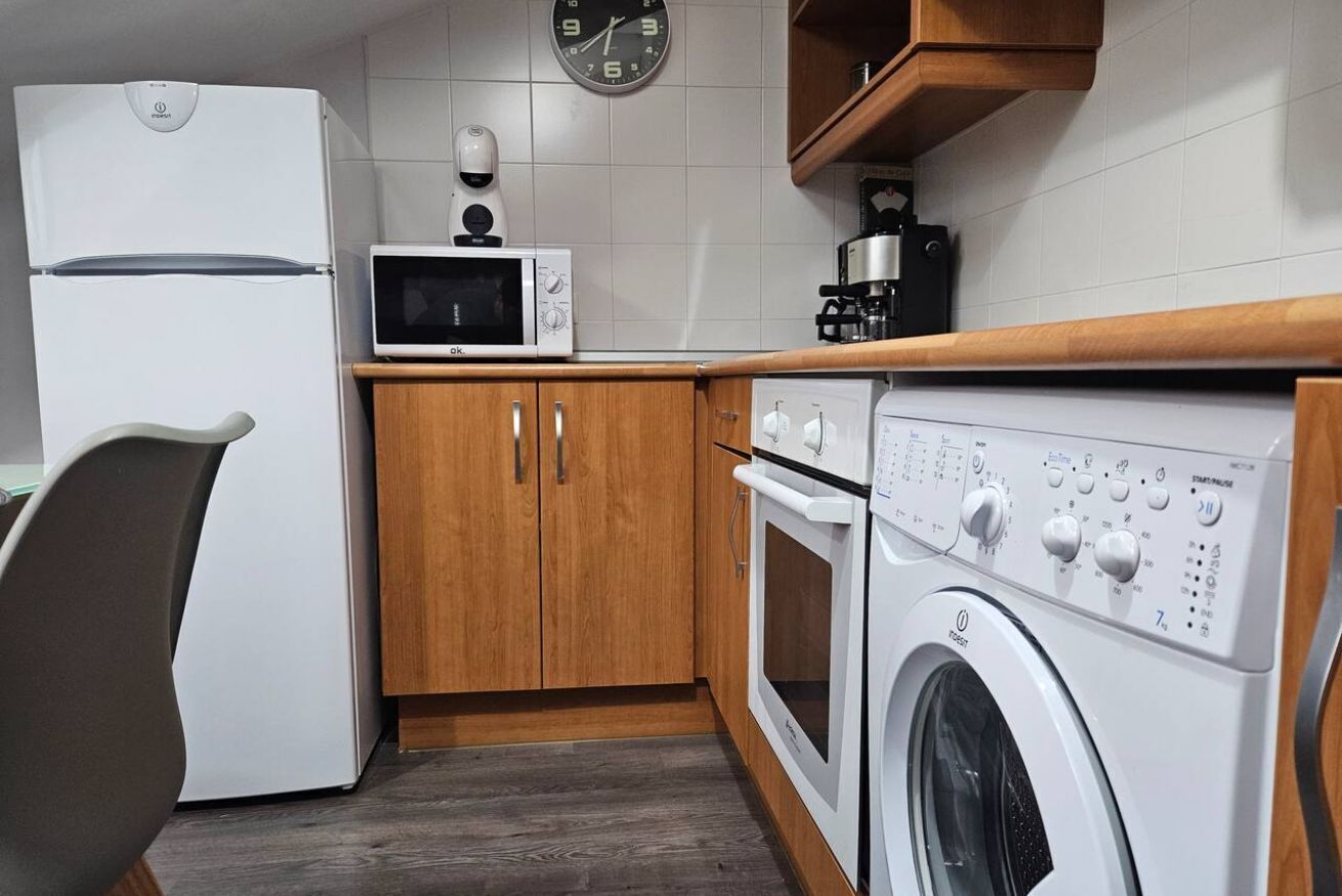 Cocina compacta equipada con refrigerador, microondas, horno y lavadora.