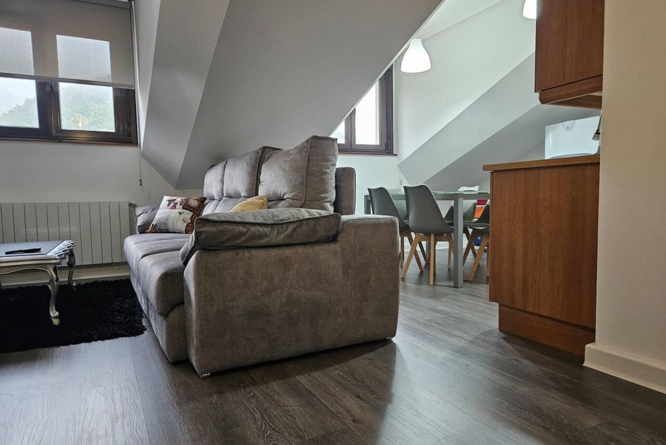 Una sala de estar moderna con un sofá, una mesa de comedor y una zona de cocina.