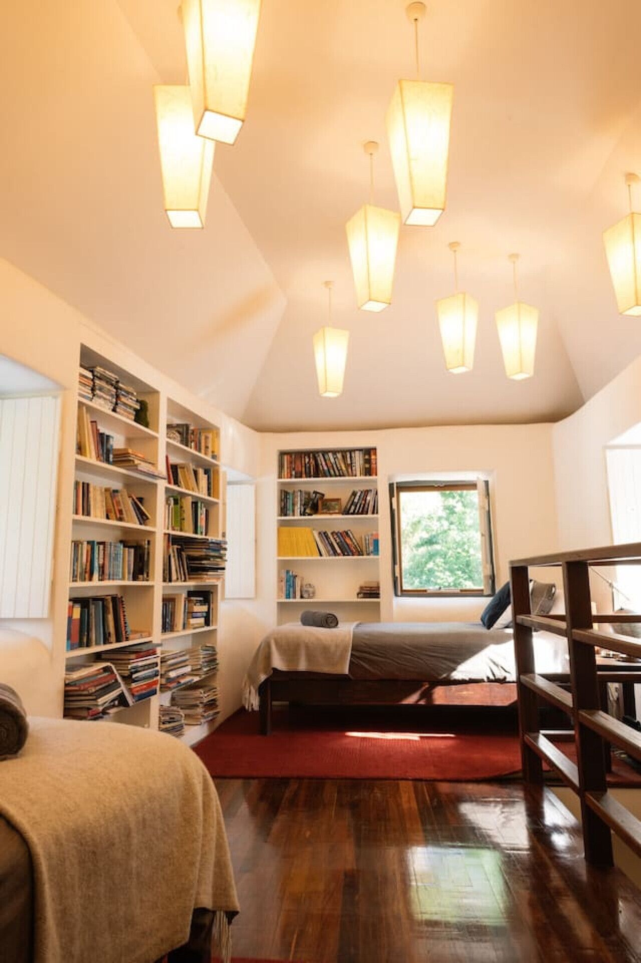 A cozy reading nook with a bed, bookshelves, and a window with natural light.
