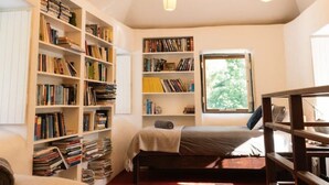 Un angolo lettura accogliente con un letto, scaffali e una finestra piena di luce naturale.