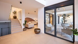 A modern interior with a staircase, a sofa, a coffee table, and a dining area with chairs.