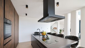 A modern kitchen with dark wood cabinets, a large island with a glass top, and a sleek black range hood.