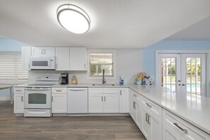 A modern kitchen with white cabinets, a built-in microwave, a stove, and a dishwasher.