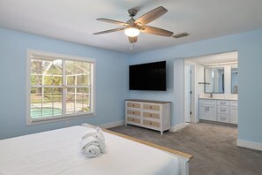 A bedroom with a bed, a ceiling fan, a TV, a dresser, a mirror, and a window with blinds. - Gorgeous Ranch Style Pool Home on One Acre Lot (Fort Myers)
