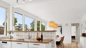 Et moderne køkken med hvide skabe, en træbordplade og et stort vindue.