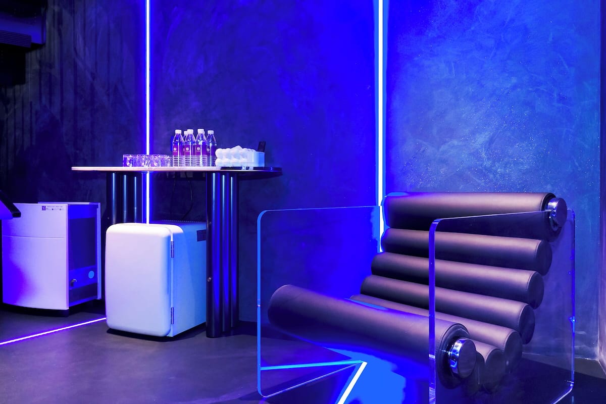 A modern room with a desk, chair, and a table with water bottles.