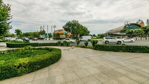 A modern building with a curved facade, a parking area with several cars, and well-maintained landscaping. - Luxury Apartment with Flame Tower View (Baku)