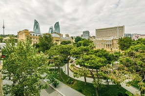 Un paisaje urbano con edificios modernos, una torre destacada y un parque con árboles.