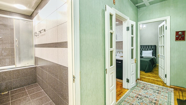 A hotel corridor with a shower area, a bedroom with a bed and a nightstand, and a bathroom with a sink and mirror. - Luxury Apartment with Flame Tower View (Baku)