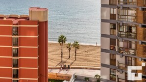 A multi-story building with balconies overlooking a beach.