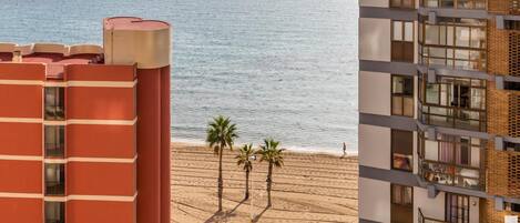 A multi-story building with balconies overlooking a beach.