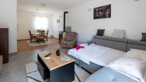 Una sala moderna con un sofá, una mesa de comedor con sillas, una mesita de madera con un jarrón y un sofá gris.