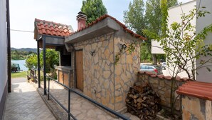 Un edificio de piedra con techo de tejas, puerta de madera y barandilla metálica.