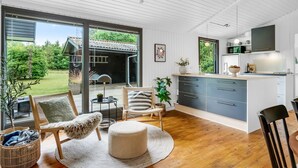 Een moderne keuken met een groot eiland, houten vloeren en een schuifdeur naar een patio met tuinmeubels.