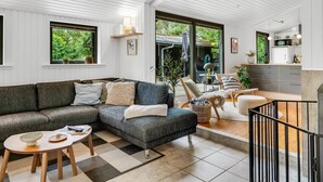 Een moderne woonkamer met een hoekbank, een salontafel en uitzicht op het groen.