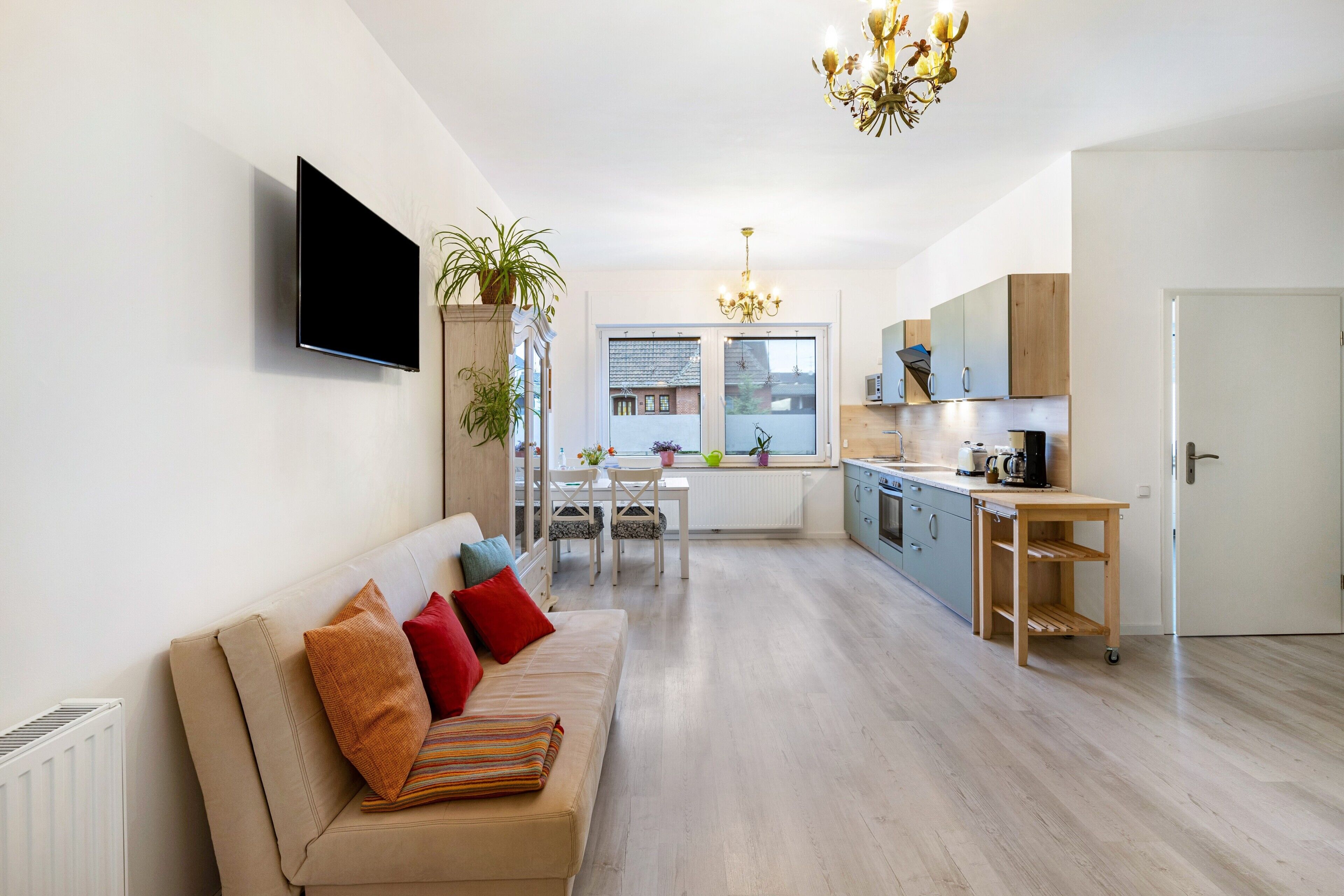 Een moderne woonkamer met een bank, televisie en een eethoek met een tafel en stoelen.
