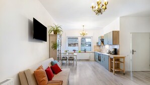 Uma sala de estar moderna com sofá, TV e área de jantar com mesa e cadeiras.