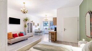 Uma sala moderna com sofá, área de jantar, cozinha e quarto com cama.