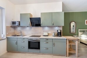 A compact kitchen with a microwave, toaster, coffee maker, and oven.