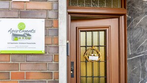 Parede de tijolos com uma placa indicando C&T Apartments, uma porta com painel de vidro e fachada de tijolos.