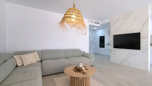 Una sala de estar moderna con un sofá modular gris, una mesa de centro redonda de madera y una lámpara colgante.